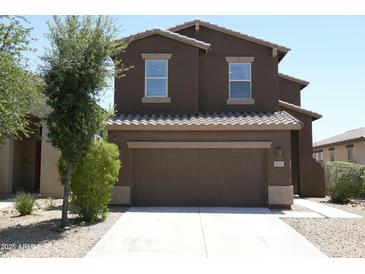 Two-story home with brown stucco, a concrete driveway, and attached two-car garage, and some landscaping at 20217 W Desert Bloom St, Buckeye, AZ 85326