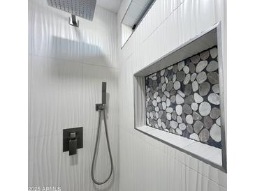 Modern shower featuring textured tile walls, pebble-style accents, and contemporary fixtures at 22261 W Tonto St, Buckeye, AZ 85326