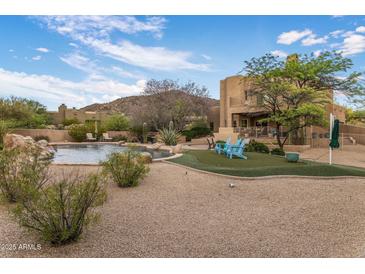 Lush backyard with a pool, putting green, and Adirondack chairs, ideal for outdoor relaxation and entertainment at 30330 N 77Th Pl, Scottsdale, AZ 85266