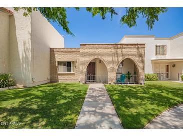 Charming townhome exterior with brick accents, grassy lawn, and covered porch entry at 7808 E Lewis Ave, Scottsdale, AZ 85257