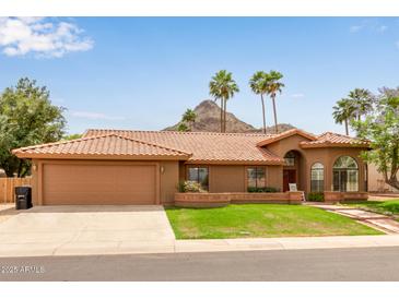 Inviting home featuring a red tile roof, well-manicured lawn, and desert landscaping with mountain views at 15430 N 19Th Way, Phoenix, AZ 85022