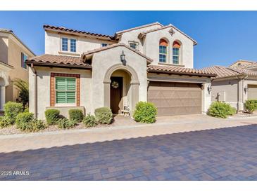 Charming two-story home with a tile roof, arched entryway, manicured bushes, and two car garage at 1952 W Yellowstone Way, Chandler, AZ 85248