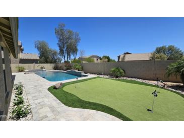 Expansive backyard featuring a pristine pool and a lush green putting area, perfect for outdoor entertainment at 28093 N Pasture Canyon Dr, San Tan Valley, AZ 85143