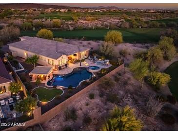 Stunning aerial view of the house and backyard featuring a pool, putting green, and desert landscaping at sunset at 31108 N 122Nd Ln, Peoria, AZ 85383