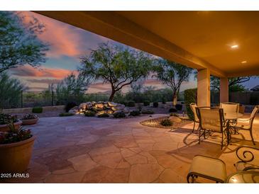 Inviting covered patio with stone flooring, water feature, and outdoor dining set for relaxing or entertaining at 40123 N Majesty Trl, Anthem, AZ 85086