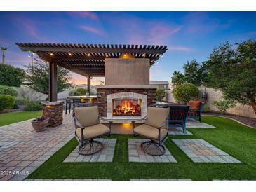 Inviting outdoor living space with a stone fireplace, pergola, and comfortable seating for relaxing evenings at 7230 W Pershing Ave, Peoria, AZ 85381