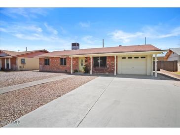 Charming single story home with a red brick facade, spacious driveway and covered porch area at 724 N Pine St, Gilbert, AZ 85233