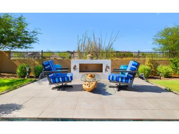 Relaxing patio area featuring comfortable chairs, a unique center table and a charming outdoor fireplace under a clear blue sky at 8040 E Jaeger St, Mesa, AZ 85207