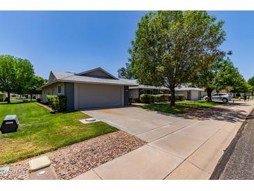 Charming single-story home featuring a spacious driveway, two-car garage, mature trees, and well-maintained lawn at 12719 W Ashwood Dr, Sun City West, AZ 85375