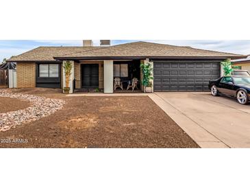 Charming single-story home with a black two-car garage and desert rock landscaping at 4441 W Windrose Dr, Glendale, AZ 85304
