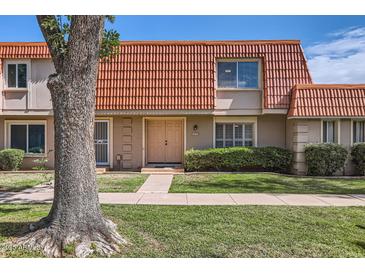 Inviting townhome featuring a unique red-tiled roof, manicured lawn, and a charming front entrance at 5166 N 83Rd St, Scottsdale, AZ 85250