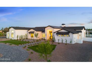 Stunning luxury home with a manicured lawn and elegant stone accents at twilight at 6147 E Desert Cove Ave, Scottsdale, AZ 85254
