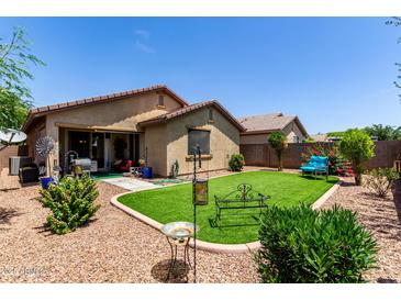 A well-maintained backyard with artificial turf, desert landscaping and covered patio at 7015 W Melody Dr, Laveen, AZ 85339