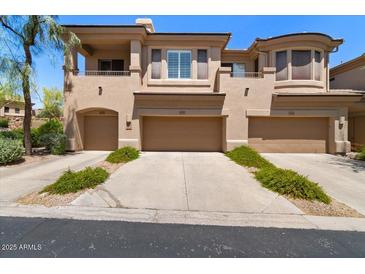 Beige townhome showcasing a three-car garage and lovely desert landscaping at 16420 N Thompson Peak Pkwy # 1002, Scottsdale, AZ 85260