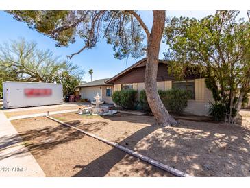 Charming single-story home with a decorative fountain and mature trees in the front yard at 2114 N 69Th Pl, Scottsdale, AZ 85257