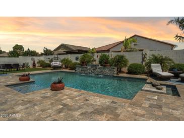 Backyard pool and waterfall feature with lush landscaping and comfortable lounging options at 41926 W Sussex Dr, Maricopa, AZ 85138