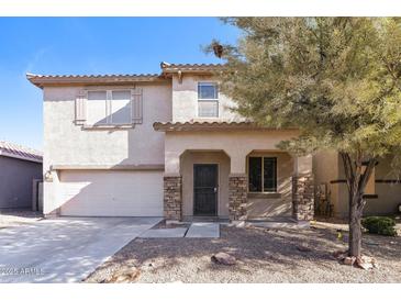 Two-story home with desert landscaping, covered porch with stone accents, and a two car garage at 42564 W Palmyra Ln, Maricopa, AZ 85138