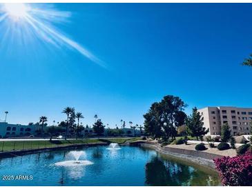 Scenic view of a pond with fountains, surrounded by landscaping and condominium buildings at 7960 E Camelback Rd # 109, Scottsdale, AZ 85251