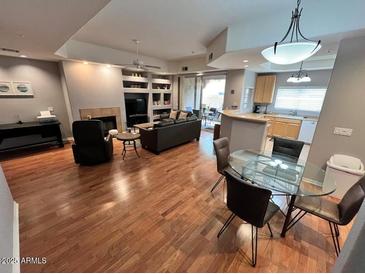 Open-concept living room boasts hardwood floors, fireplace, and sliding glass doors to an outdoor patio at 8245 E Bell Rd # 103, Scottsdale, AZ 85260