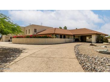 Beige home featuring a concrete driveway, desert landscaping, and a red tiled roof at 9622 N 112Th Ave, Sun City, AZ 85351