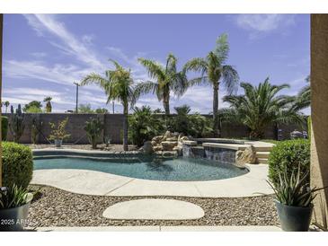Inviting pool area with rock waterfall, lush landscaping, and a spa for ultimate relaxation at 1123 E Shepherds Way, Casa Grande, AZ 85122