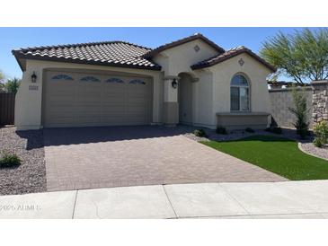 Charming single-story home featuring a well-manicured yard and a brick-paved driveway leading to a two-car garage at 24146 N 162Nd Ln, Surprise, AZ 85387