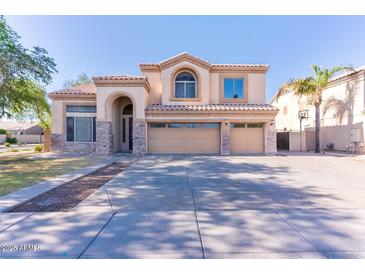 Two-story home with a three-car garage, neutral stucco, stone accents, and a well-manicured front lawn at 2880 E Nunneley Rd, Gilbert, AZ 85296