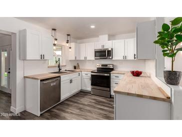 Bright kitchen with white cabinets, stainless steel appliances, wood countertops, and a modern design at 39 N Maple St, Mesa, AZ 85205