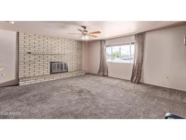 Spacious living room with a brick fireplace and large window providing ample natural light at 501 E Hill Dr, Avondale, AZ 85323