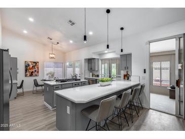 Bright open-concept kitchen with quartz countertops, central island, pendant lights, and stainless steel appliances at 8449 W Rockwood Dr, Peoria, AZ 85382