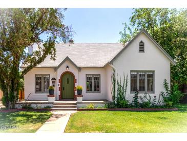 Charming single-story home featuring a white stucco exterior, green door, and lush landscaping at 917 W Willetta St, Phoenix, AZ 85007
