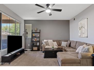 Comfortable living room with a ceiling fan and a large sectional sofa and dark gray accent wall at 11680 E Sahuaro Dr # 2011, Scottsdale, AZ 85259
