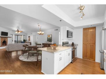 Open-concept kitchen and dining area with granite countertops, stainless steel appliances, and wood flooring at 3031 N Civic Center Plz # 317, Scottsdale, AZ 85251