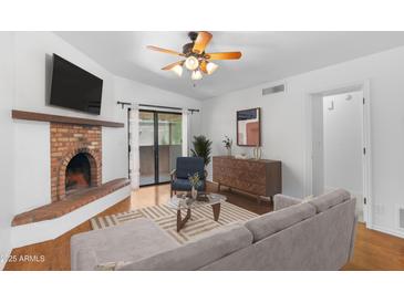Bright living room features a brick fireplace, ceiling fan, and sliding doors to the outdoor patio at 3031 N Civic Center Plz # 317, Scottsdale, AZ 85251