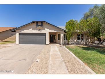 Charming single-story home featuring a gray garage door and manicured front yard at 45 S Rita Ln, Chandler, AZ 85226
