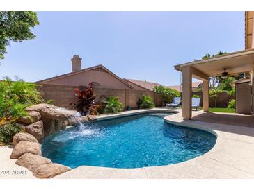 Backyard pool and waterfall feature, surrounded by lush landscaping for a serene retreat at 6787 W Saddlehorn Rd, Peoria, AZ 85383