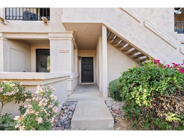 Charming entryway with desert landscaping, stairs, and a secure black metal screen door at 9708 E Via Linda Rd # 1350, Scottsdale, AZ 85258