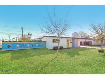 Charming single-story home featuring a bright yellow front door and a beautifully manicured lawn at 12453 N 29Th Ave, Phoenix, AZ 85029
