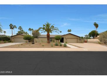 Charming single-story home featuring a neutral color palette, desert landscaping, and a spacious driveway at 14014 N 57Th Way, Scottsdale, AZ 85254