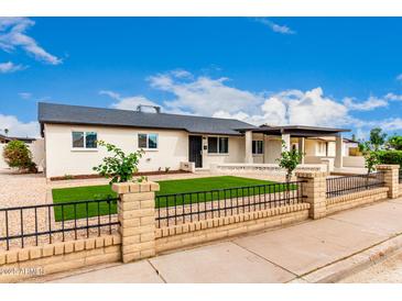 Charming single-story home with brick fence, gravel yard, and green turf in front of house at 1852 N Grand St, Mesa, AZ 85201