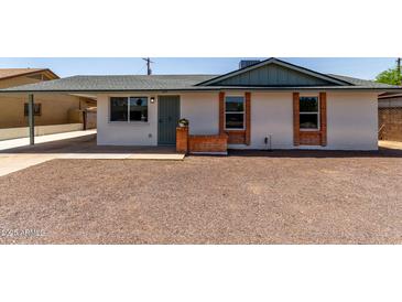 Charming single-story home featuring a brick accent, gravel landscaping, and a covered carport at 927 E Greenway Rd, Phoenix, AZ 85042