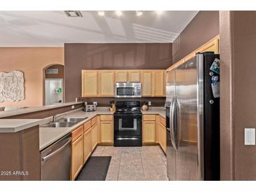 Well-lit kitchen featuring stainless steel appliances, ample cabinetry, and a convenient breakfast bar area at 1350 S Greenfield Rd # 2205, Mesa, AZ 85206
