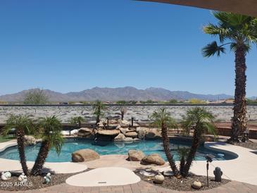 Stunning backyard pool with rock waterfall feature, tropical palms and beautiful mountain views at 14725 S 182Nd Dr, Goodyear, AZ 85338