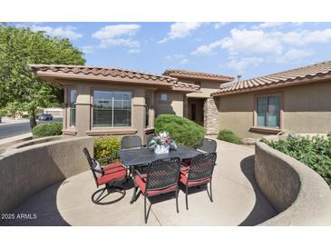 Charming patio with black metal table, chairs, and lovely landscaping, perfect for outdoor dining and relaxation at 16974 W Marcos De Niza Dr, Surprise, AZ 85387