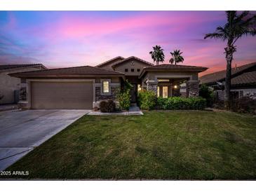 Beautiful home at twilight with lush green grass, desert landscaping, and a two-car garage at 2156 W Periwinkle Way, Chandler, AZ 85248