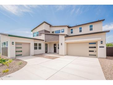 Modern two-story home featuring a three-car garage, neutral stucco, and contemporary design elements, set against a bright blue sky at 35234 N Barley St, San Tan Valley, AZ 85144