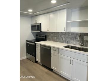 Close up of remodeled kitchen features stainless appliances, white cabinetry, and quartz countertops at 540 E Royal Palms Dr, Mesa, AZ 85203
