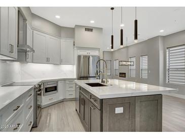 Modern kitchen with gray cabinets, a large island, stainless steel appliances, and stylish pendant lighting at 7525 E Gainey Ranch Rd # 118, Scottsdale, AZ 85258