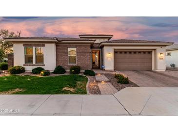 Charming home featuring manicured lawn, beautiful brick accents, and a lovely paver driveway leading to a two-car garage at 2052 E Scorpio Pl, Chandler, AZ 85249