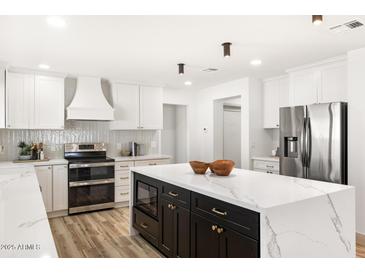 Bright kitchen featuring an island with a waterfall countertop, stainless steel appliances, and white cabinets at 2353 N 51St Pl, Phoenix, AZ 85008